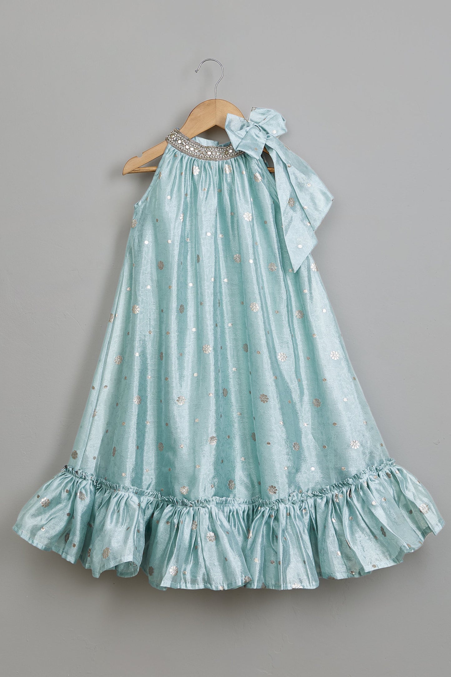 Light blue dress with ruffled hem on a hanger against a gray background.