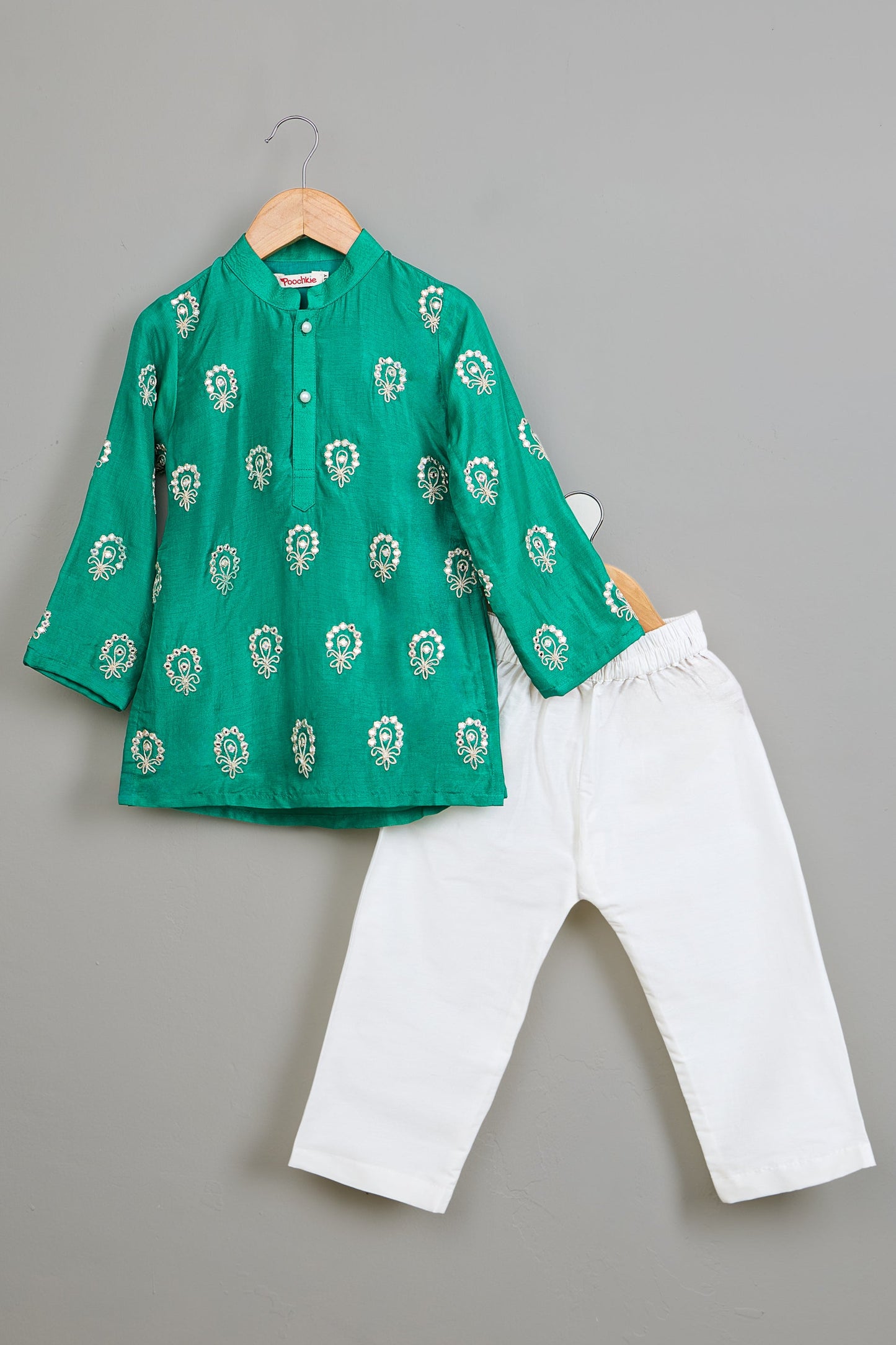 Green embroidered kurta and white pants on a gray background