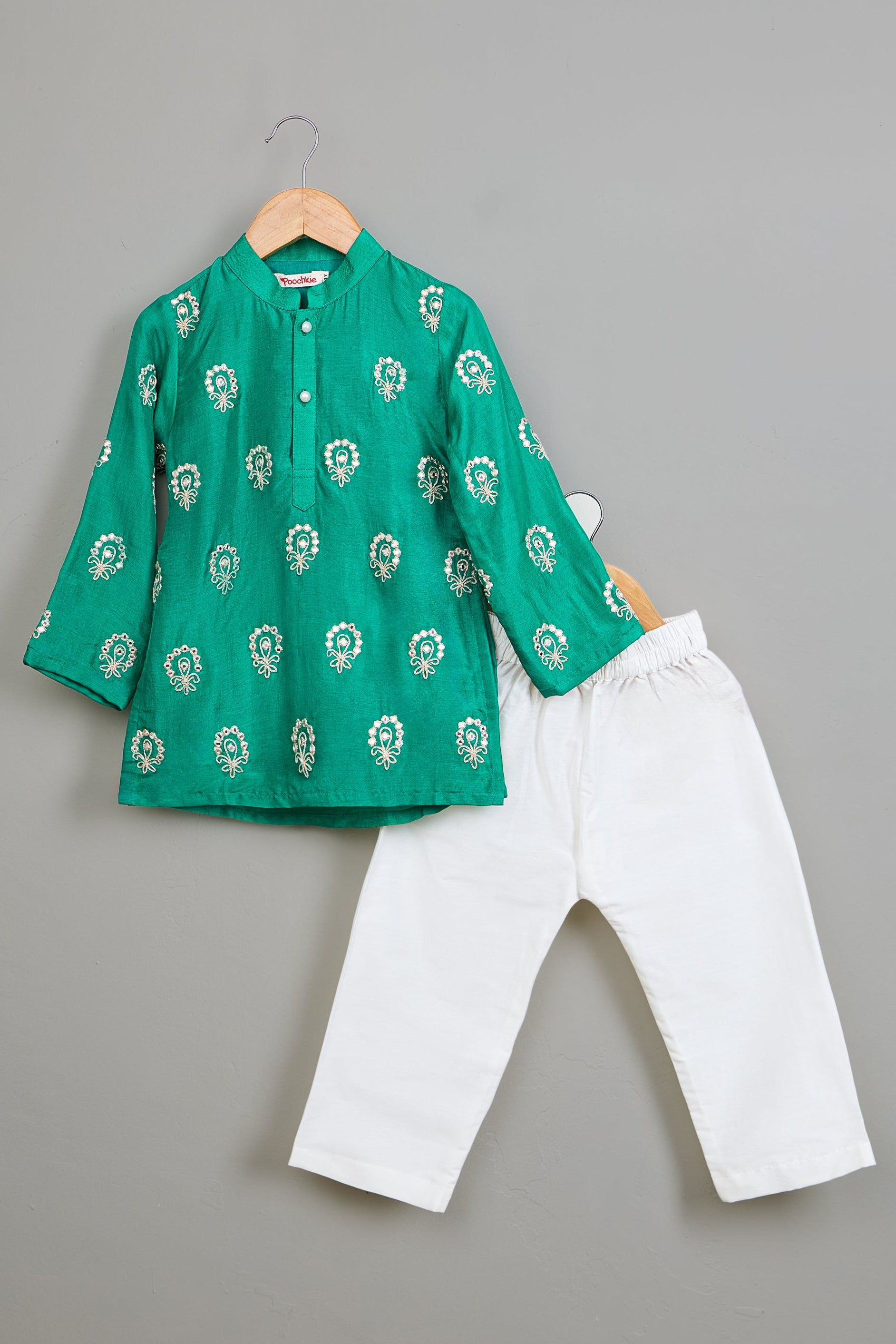 Green embroidered kurta and white pants on a gray background