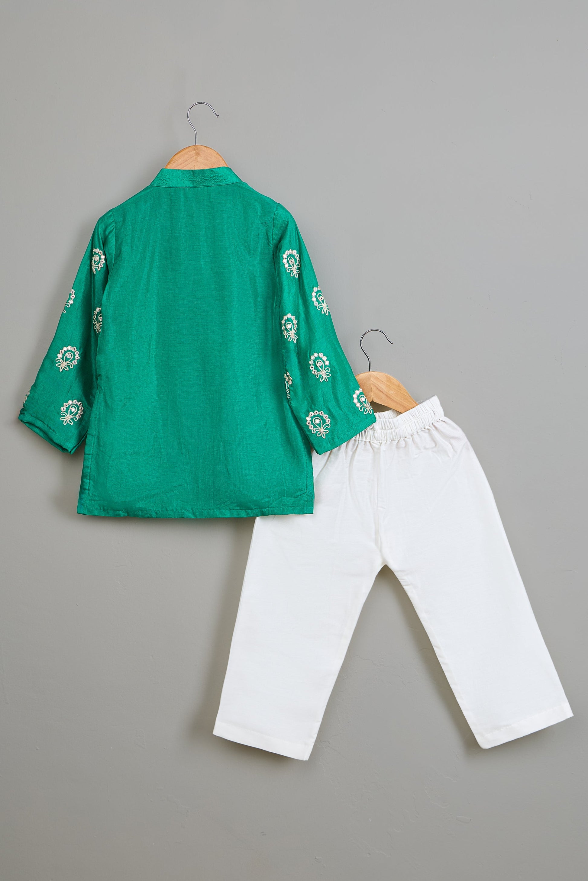Green embroidered kurta and white pants on a gray background