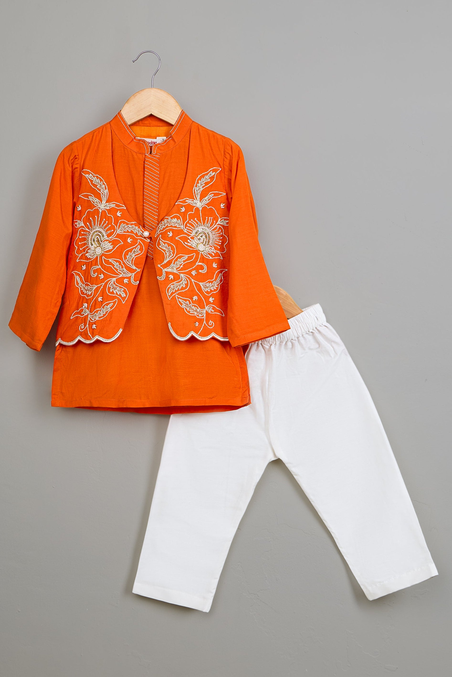 Orange embroidered Kurta and white pants on a gray background