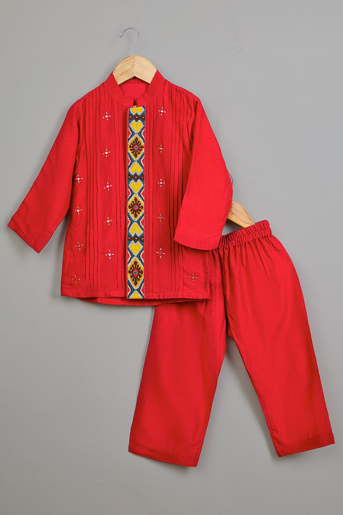 Red boys kurta outfit with embroidered design on a gray background